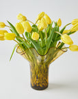 Yellow tulips in a decorative glass vase on a light background