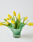 Green vase with yellow tulips on a white background