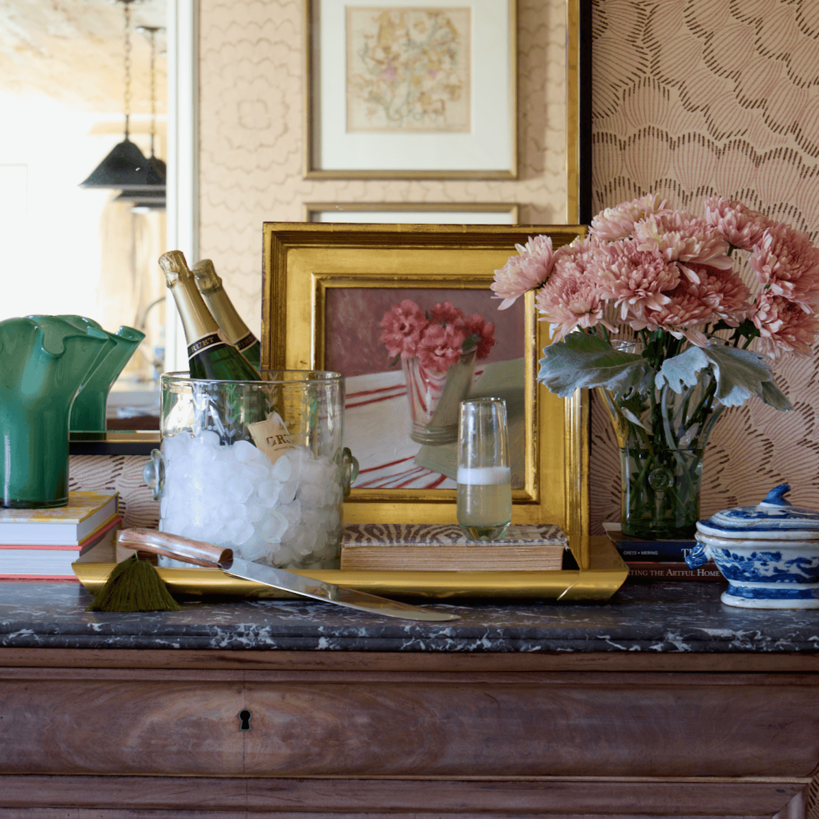 Decorative setting with champagne, ice, vase, and flowers on a table.