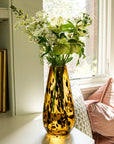Vase with flowers on a windowsill next to a pink cushion