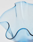 Blue glass vase with wavy edge on a light gray background