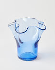 Blue glass vase with wavy design on a light gray background