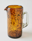 Toroise shell patterned brown glass pitcher on a white background