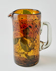 Spotted brown glass pitcher with a handle on a white background