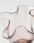 Pink glass vase with wavy design on a light background