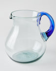 Clear glass pitcher with a blue handle on a white background