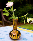 Small amber glass vase with flowers on a table outdoors