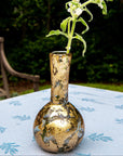 Gold decorative vase with a plant on a table outdoors