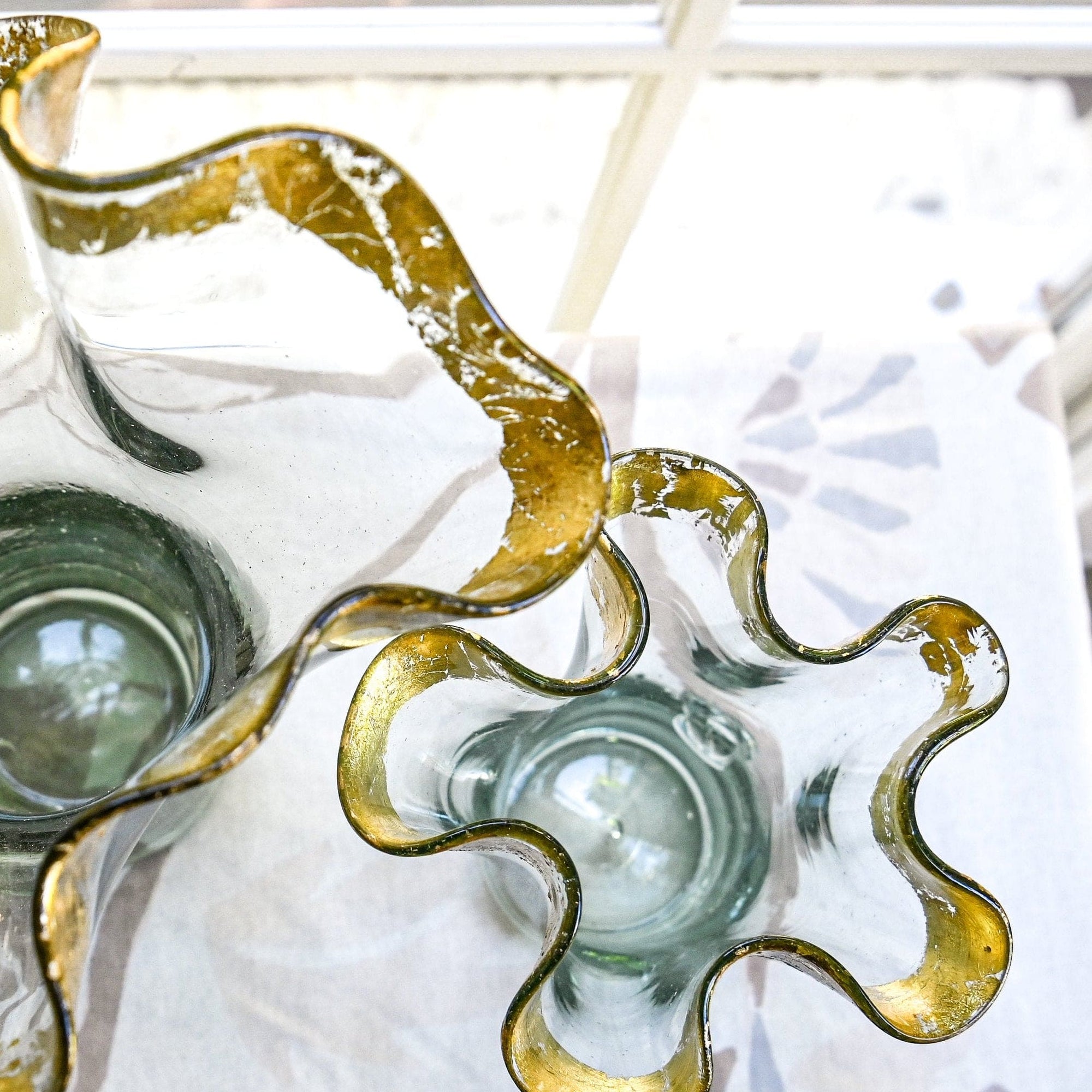 Clear glass vase with a wavy design with the rim covered in 14k gold leaf
