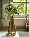 Vase with flowers on a kitchen counter next to a window