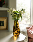 Vase with flowers on a windowsill next to a sofa with pillows