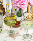 Table setting with cocktails, limes, chips, and flowers on a floral tablecloth.