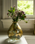 Glass vase with flowers on a kitchen counter near a window