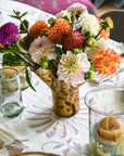 Clear vase covered in 14k gold leaf on a table together with other tablewares