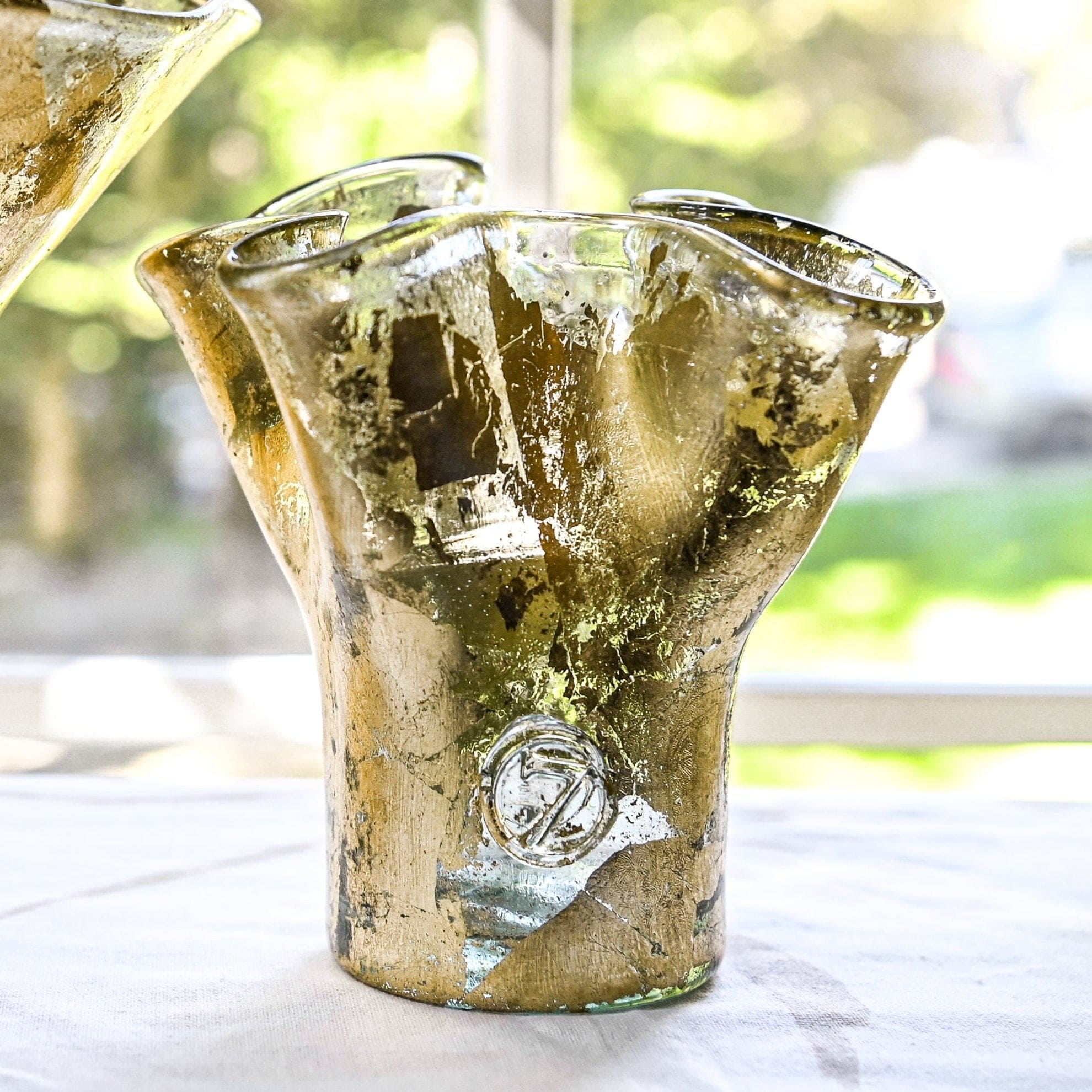 A handcrafted gold leaf colored glass vase with a lettuces leaf design on a clear base, showing subtle variations in color and form.