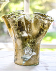 A handcrafted gold leaf colored glass vase with a lettuces leaf design on a clear base, showing subtle variations in color and form.
