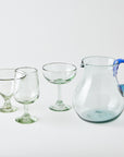 Set of clear glassware including a pitcher with a blue handle on a white background