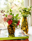Two vases with flowers on books by a window