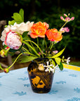 Vase with colorful flowers on a tablecloth outdoors