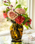 Vase with pink and red flowers on a table by a window
