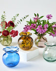 Collection of colorful glass vases with flowers on a white background