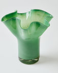 Green glass vase with ruffled top on a white background