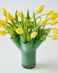 Green vase with yellow tulips on a white background
