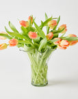 Clear glass vase with peach-colored tulips on a light gray background