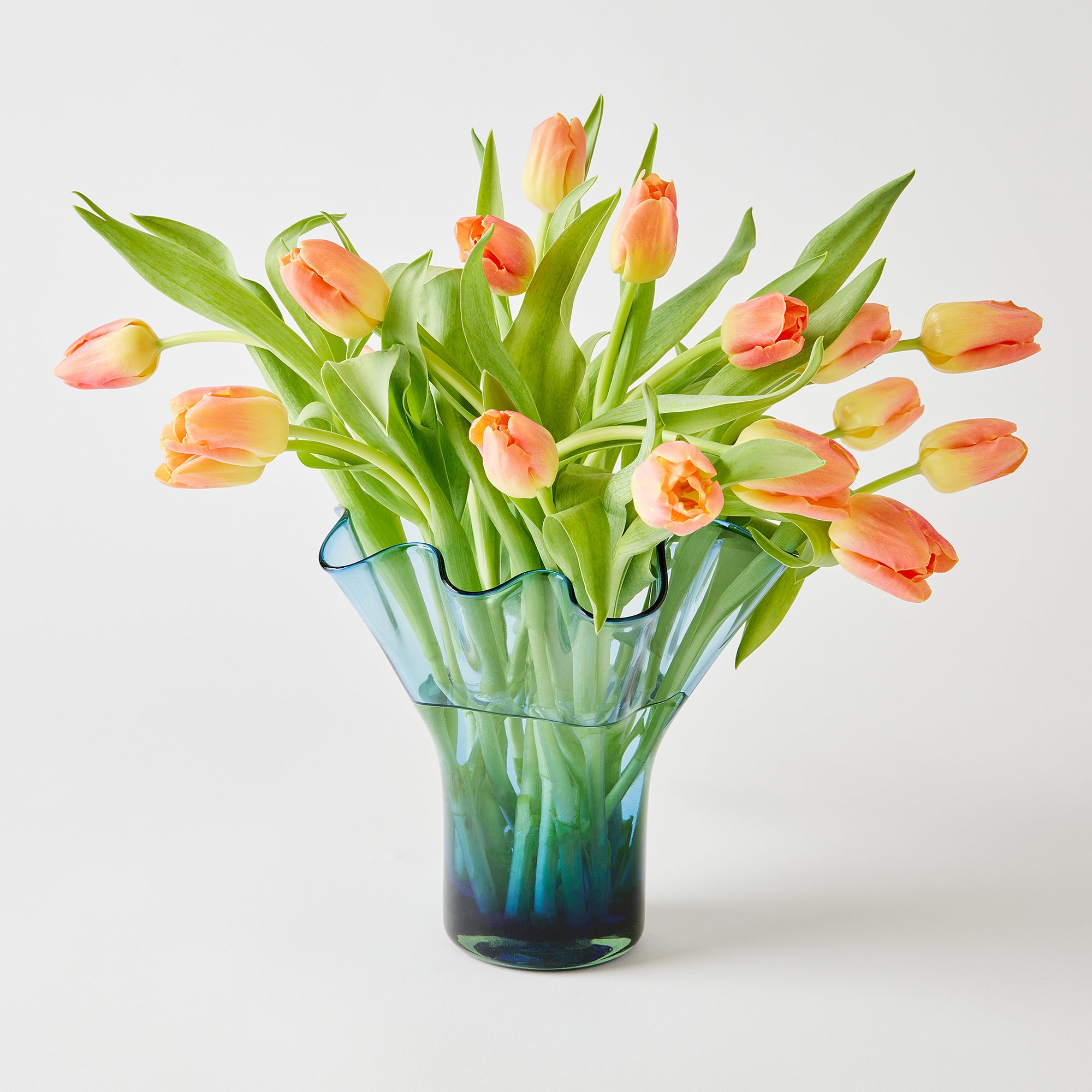 Clear glass vase with peach-colored tulips on a white background
