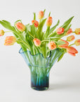 Clear glass vase with peach-colored tulips on a white background