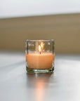 A clear glass votive with hand-etched stars on it, reflecting light.