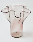 Pink glass vase with wavy design on a white background