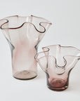 Two pink glass vases with wavy designs on a white background
