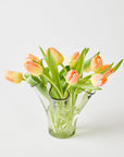 Clear glass vase with peach-colored tulips on a light background