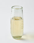 Clear glass etched with ferns and dots filled with champagne on a light gray background