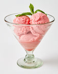 Strawberry ice cream in a footed dish glass  etched with stars with mint leaves on a white background