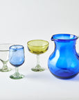 Set of colorful glassware including a blue pitcher and various glasses on a white background