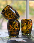 Three tortoiseshell patterned glasses on a surface with a blurred outdoor background