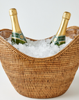 Two bottles of champagne in a woven ice bucket on a light background
