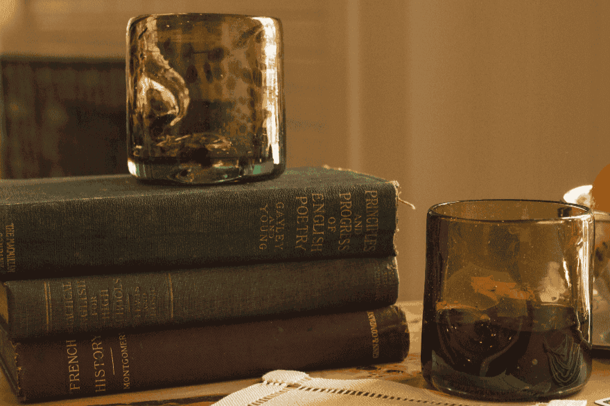 Stack of books with a decorative glass item on top, set against a warm-toned background.
