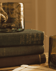 Stack of books with a decorative glass item on top, set against a warm-toned background.