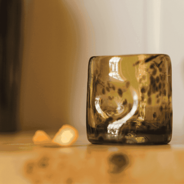 Brown glass block on a reflective surface with a blurred background