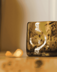 Brown glass block on a reflective surface with a blurred background