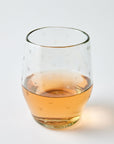 Clear glass with star patterns filled with a amber liquid on a light gray background