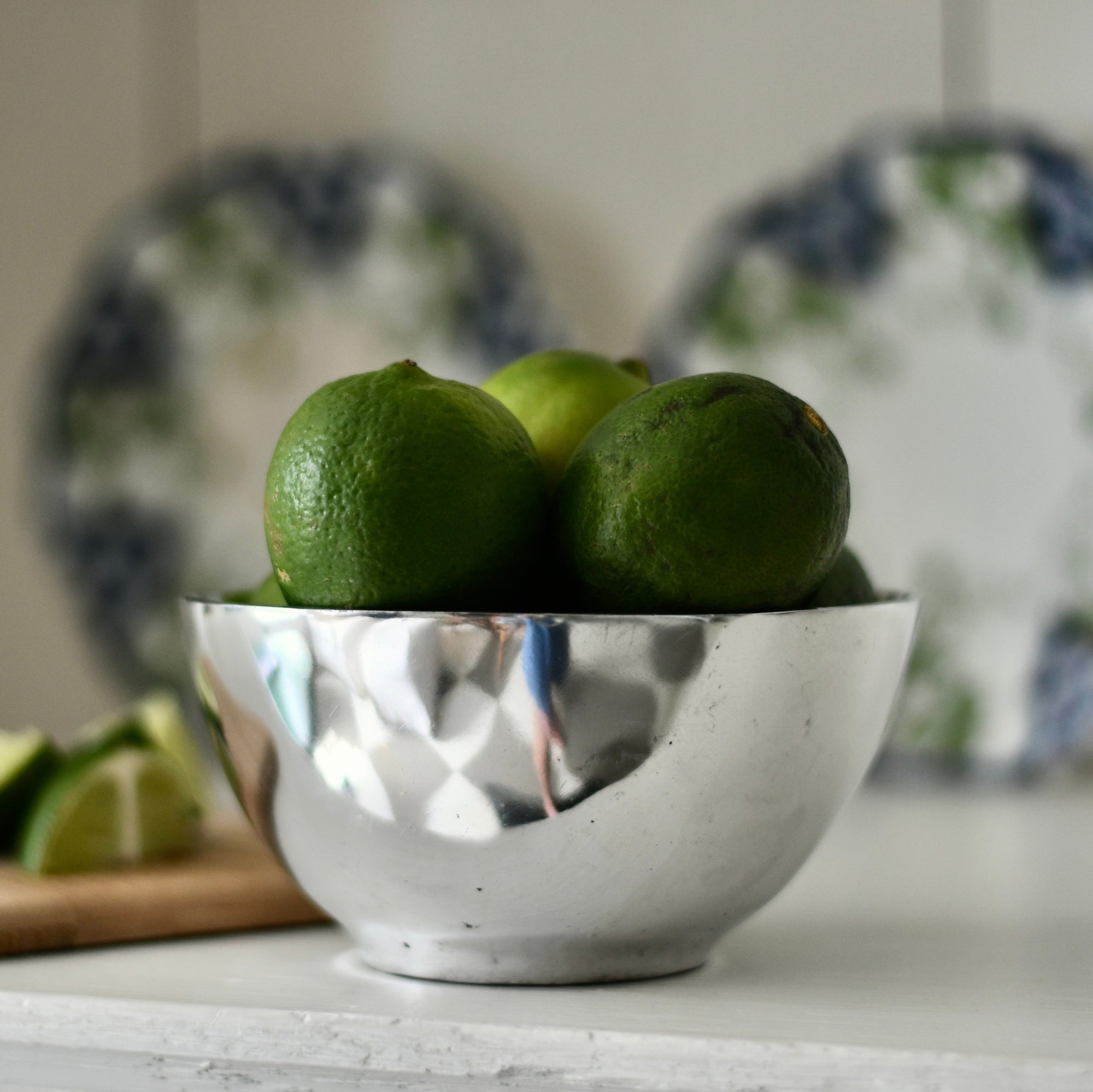 Green limes in a silver bowl with a blurred background