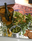 Decorative table setting with wine, glasses, and a bowl of olives on a tray.
