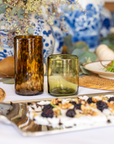 Decorative table setting with tortoiseshell and green glasses, plates, and a floral arrangement.