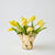 Gold vase with yellow tulips on a light gray background