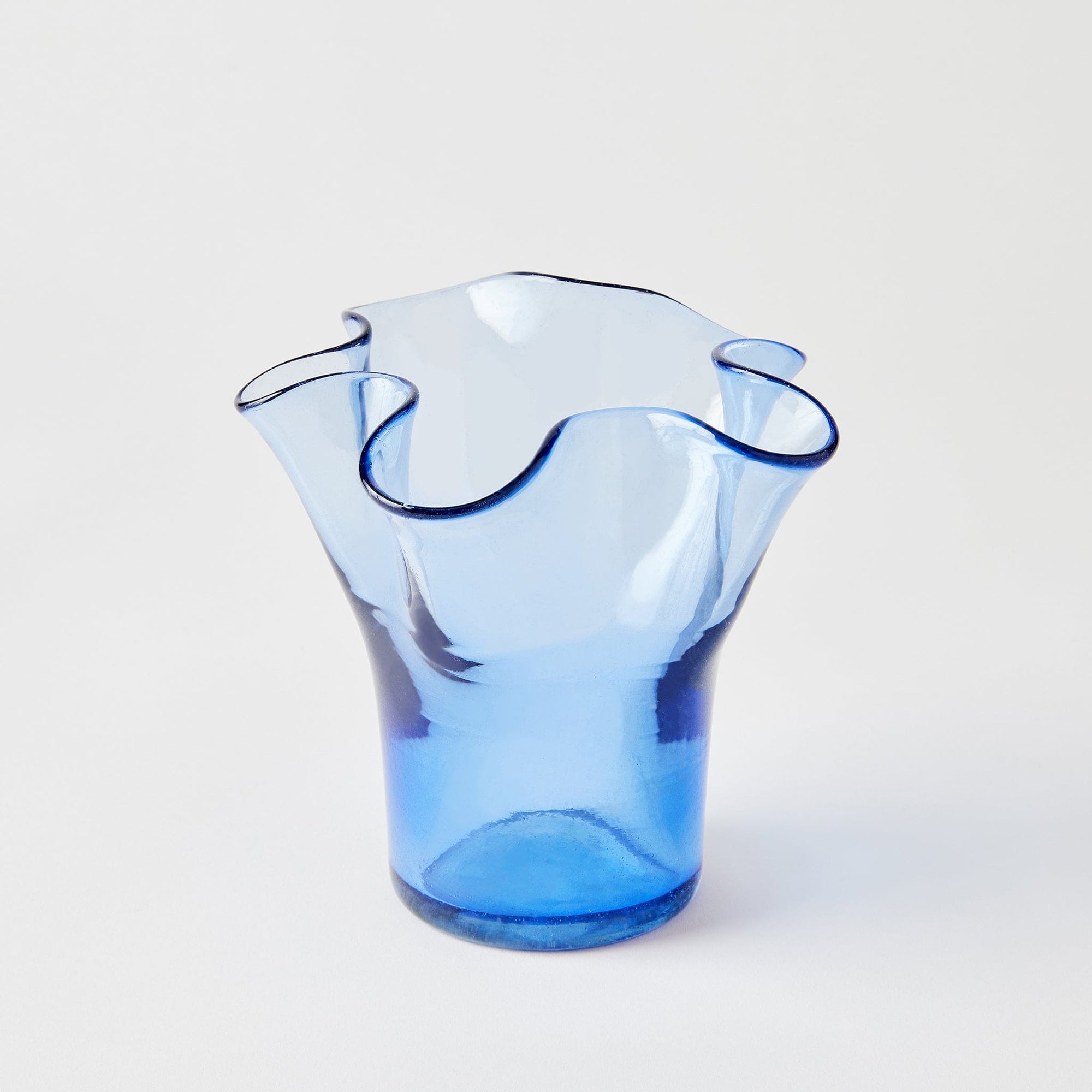 Blue glass vase with wavy design on a light gray background