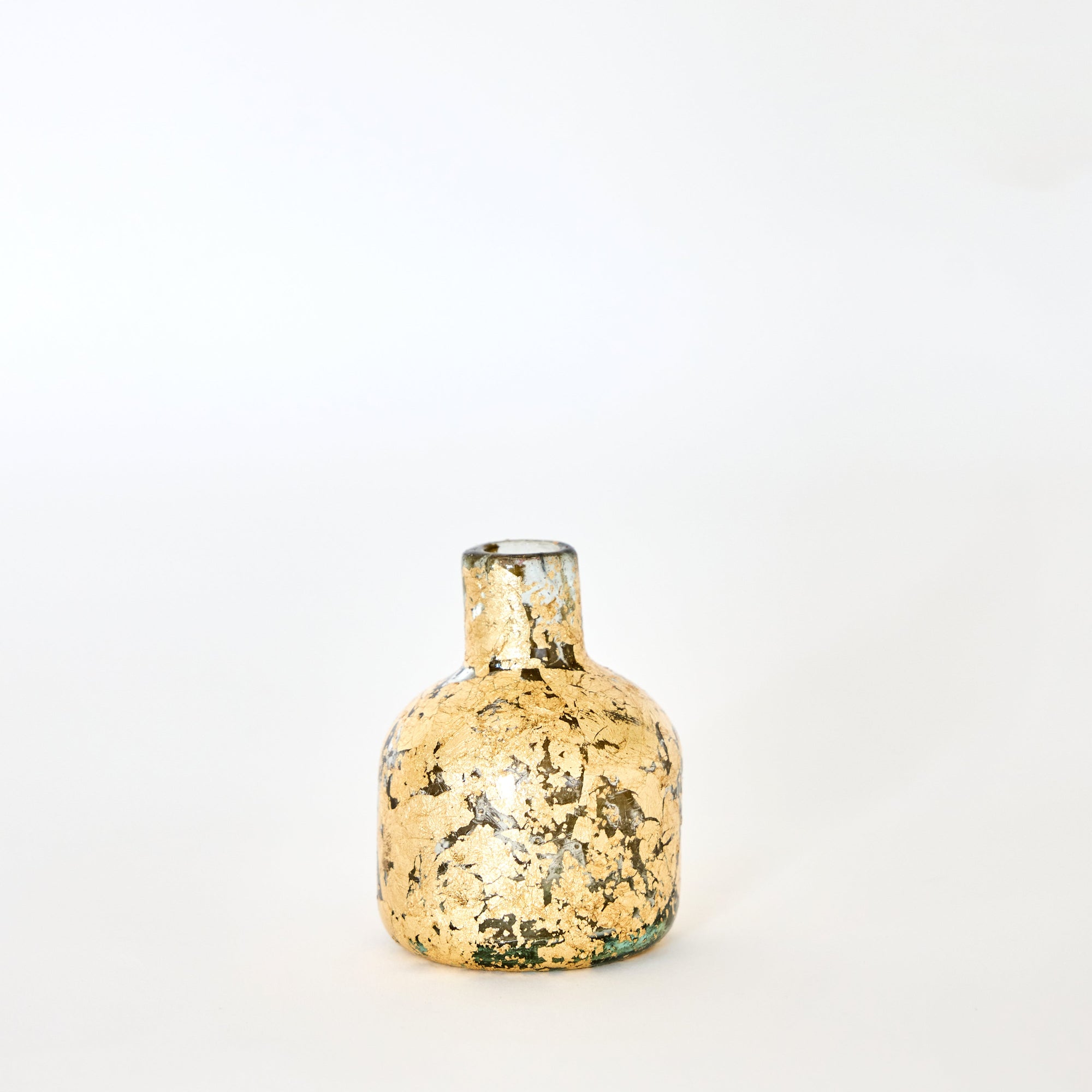 A small handmade glass vase with gold leaf patterns, displayed against a neutral background.